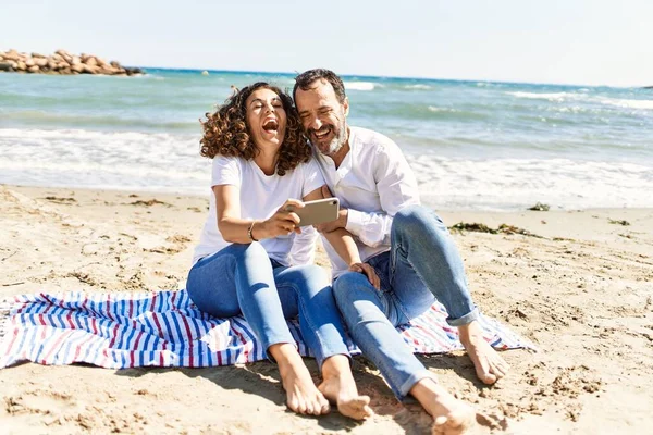 Coppia Ispanica Mezza Età Con Smartphone Seduto Sull Asciugamano Spiaggia — Foto Stock