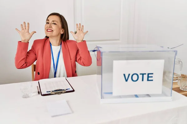 自信と幸せを笑顔ながら指の番号10を示し 指差す投票によって座っている政治選挙で美しい中年のヒスパニック女性 — ストック写真