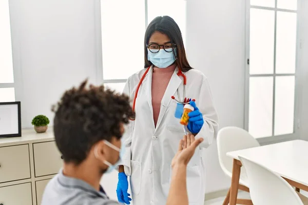 若いラテン語の医者の女性与えボトルの薬へ男に医療室 — ストック写真