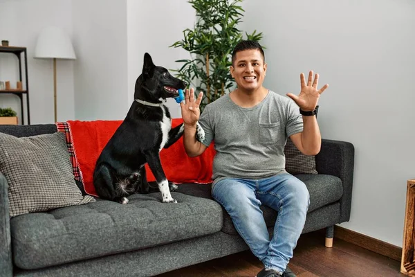 Jovem Latino Homem Cão Sentado Sofá Casa Mostrando Apontando Para — Fotografia de Stock