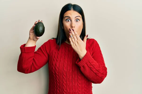 Vacker Brunett Kvinna Håller Avokado Täcker Munnen Med Handen Chockad — Stockfoto