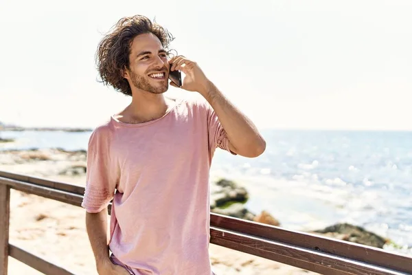 Ung Latinamerikansk Man Ler Glad Talar Smartphone Stående Stranden — Stockfoto