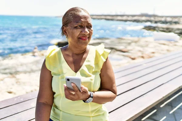 Mujer Afroamericana Mayor Usando Teléfono Inteligente Sentado Banco Playa —  Fotos de Stock