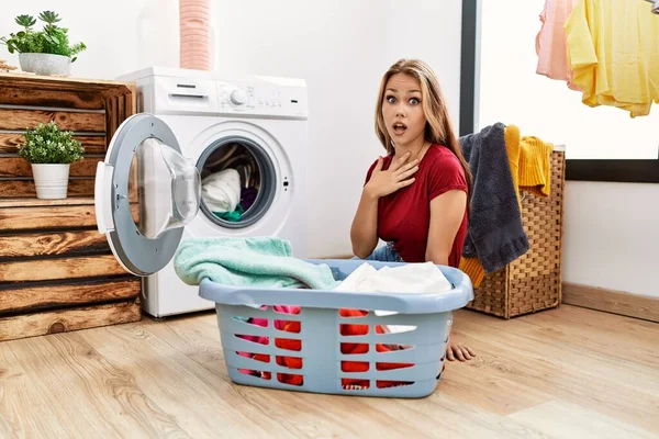 若い白人女性は洗濯機に汚れた洗濯機を入れて怖がらせ 驚きのために口を開けて驚いて 不信顔 — ストック写真