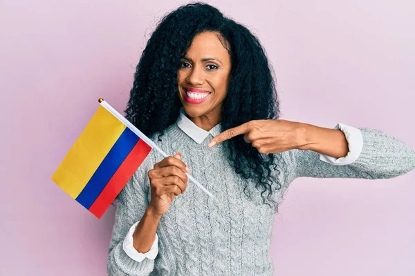 Mujer Afroamericana Mediana Edad Sosteniendo Bandera Colombia Sonriendo Feliz Señalando — Foto de Stock