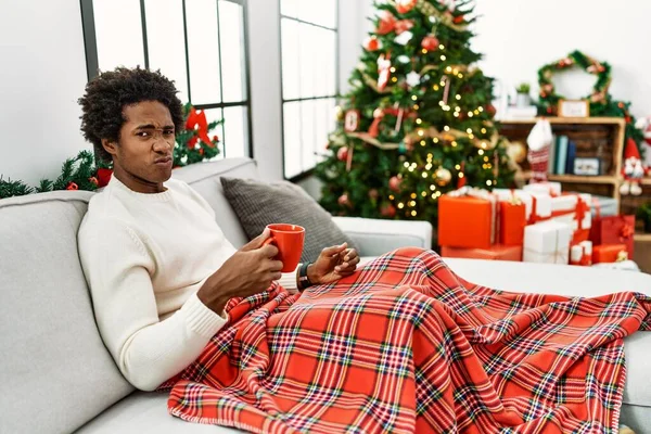 Hombre Afroamericano Joven Sentado Sofá Bebiendo Café Por Árbol Navidad — Foto de Stock