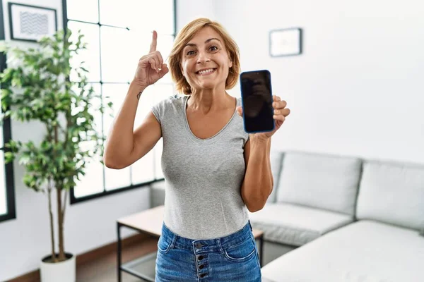Medelålders Blond Kvinna Som Arbetar Håller Smartphone Visar Skärmen Förvånad — Stockfoto