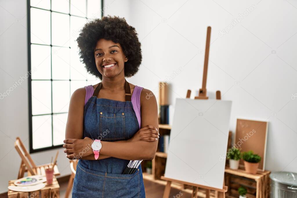 Young african american woman with afro hair at art studio happy face smiling with crossed arms looking at the camera. positive person. 