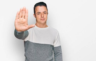 Kış süveteri giyen yakışıklı genç adam avucunun içi gibi şarkı söylemeyi kesiyor. Yüzünde olumsuz ve ciddi bir jest olan uyarı ifadesi. 