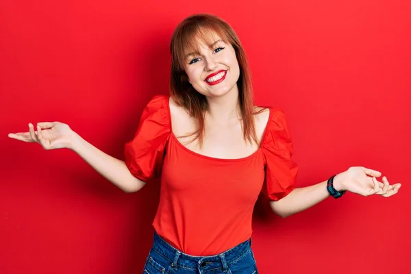 Kırmızı Tişörtlü Kızıl Saçlı Genç Kadın Gülümseyerek Avuçlarını Açıyor Sunuyor — Stok fotoğraf
