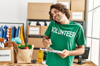 Hayır kurumunda akıllı telefon kullanarak mutlu gülümseyen genç İspanyol gönüllü adam..