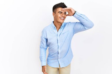 Tecrit edilmiş arka planda duran İspanyol gömlekli genç adam çok mutlu ve tebessüm ediyor. arama kavramı. 