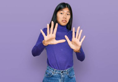 Güzel, genç Asyalı kadın gündelik giysiler giyip korku ifadesinden korkuyor ve dehşete düşüyor. El hareketlerini bırak, şok içinde bağır. panik konsepti. 