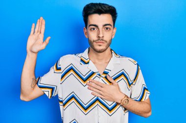 Latin asıllı genç adam, gündelik giysiler giyip, el pençe divan yemin ederek sadakat yemini ediyor. 