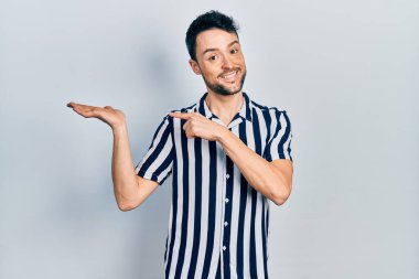 Gündelik kıyafetler giyen genç İspanyol adam kameraya hayret ediyor ve gülümsüyor.. 