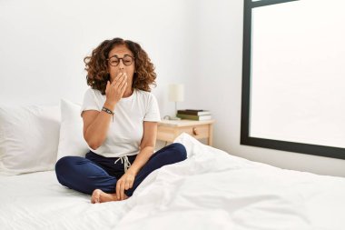 Orta yaşlı İspanyol bir kadın evde yatağında oturup ağzını eliyle kapatmaktan sıkılmış. Huzursuz ve uykulu.. 