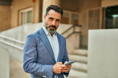 Şehirdeki akıllı telefondan gülümseyen orta yaşlı bir işadamı..