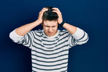 Kulakları genişlemiş, sıradan çizgili tişört giyen, baş ağrısı çeken, çaresiz ve stresli genç beyaz bir çocuk. Çünkü ağrı ve migren. Eller başının üstünde.. 