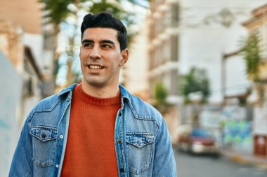 Genç İspanyol adam gülümseyerek şehirde mutlu mesut dikiliyor..