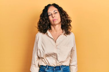 Orta yaşlı İspanyol kadın günlük kıyafetler giyiyor ve yüzünde ciddi bir ifadeyle rahatlıyor. Basit ve doğal bir şekilde kameraya bakıyorsun.. 