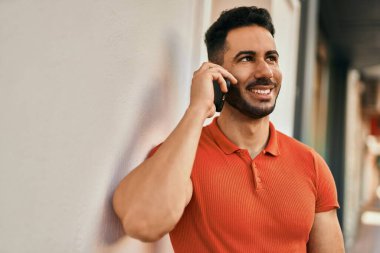 Genç İspanyol adam gülümsüyor. Şehirdeki akıllı telefondan konuşuyor..