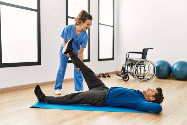 Klinikte hareket kabiliyeti egzersizi yapan genç bir adam..