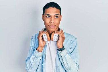 Genç Afro-Amerikalı adam müzik dinliyor kulaklık takıyor. Gülümsüyor, yan tarafa bakıyor ve düşünüyor.. 