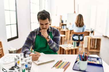 Sanat stüdyosundaki genç sanatçı kendini kötü hissediyor ve soğuk algınlığı veya bronşitin belirtisi olarak öksürüyor. sağlık hizmeti kavramı. 