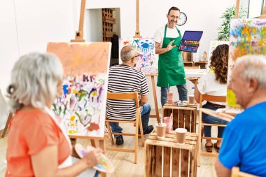 Bir grup orta yaşlı öğrenci resim stüdyosunda resim dersi alıyor..