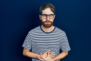 Beyaz, sakallı, çizgili tişörtlü ve eli göbeğinde gözlüklü bir adam. Çünkü hazımsızlık, acı verici bir hastalık ve kendini iyi hissetmiyor. Ağrı kavramı. 