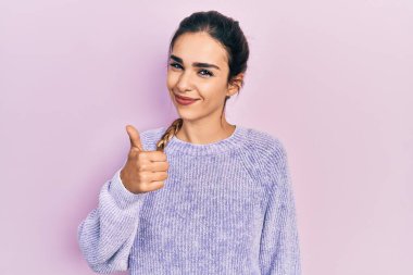 Gündelik kıyafetler giyen genç İspanyol kız elleriyle mutlu bir jest yapıyor. Kameraya bakıp başarıyı gösteren ifade. 