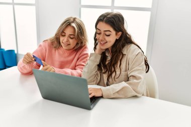 Genç çift evde dizüstü bilgisayar ve kredi kartı kullanıyor..