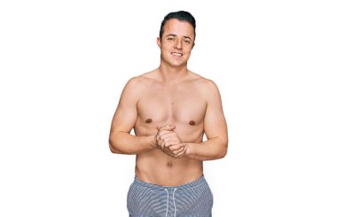 Yakışıklı, mayo giyen, elleri bağlı ve gülümseyen rahat ve neşeli bir genç. Başarı ve iyimserlik 