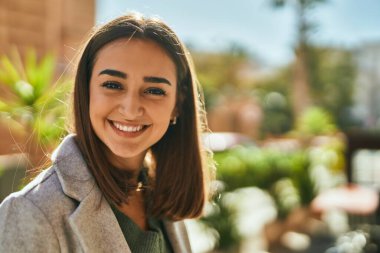 Genç İspanyol kız gülümseyerek şehirde mutlu mesut dikiliyor..