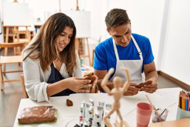 Sanat okulunun masasında oturmuş mutlu bir şekilde modellik yapan iki öğrenci..