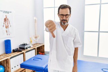 Sakallı orta yaşlı bir adam ağrı kesici kliniğinde çalışıyor. Mutsuz ve sinirli görünüyor. Reddedilmiş görünüyor. kötü ifade. 