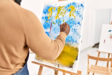 Arkaya bakan Afrikalı Amerikalı ressam resim stüdyosunda resim çiziyor..