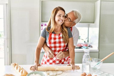 Orta yaşlı İspanyol çift mutlu gülümsüyor ve mutfakta hamur yoğuruyorlar..