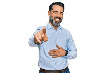 Sakallı, iş gömleği giyen orta yaşlı bir adam sana gülüyor, eli vücudunun üzerinde kamerayı işaret ediyor, yüz ifadesi utanç verici. 