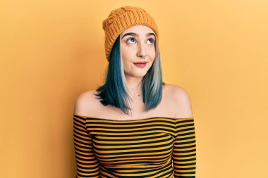 Yün şapka takan, gülümseyen, yan bakan ve düşünen genç modern bir kız.. 