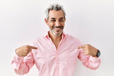 Orta yaşlı İspanyol bir adam soyutlanmış arka planda duruyor. Kendine güveni tam görünüyor. Kendini gururlu ve mutlu bir şekilde gösteriyor.. 