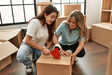 Genç ve güzel bir çift gülümsüyor. Yeni evlerinde karton kutular paketliyorlar..
