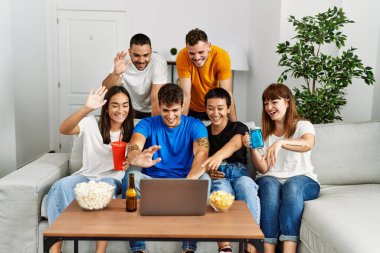 Bir grup genç arkadaş, evde bilgisayarlarını kullanarak mutlu bir şekilde görüntülü arama yapıyorlar..