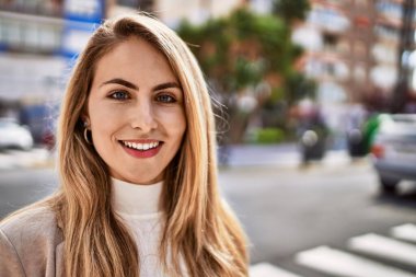 Sokakta kendinden emin gülümseyen genç sarışın kadın