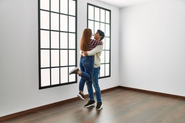 Genç İspanyol çift mutlu bir şekilde gülümsüyor ve boş yeni evlerinde birbirlerine sarılıyorlar..