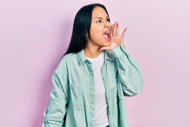 Güzel İspanyol kadın, burun piercingli, sıradan yeşil ceket giyen, el ve ağızla bağırıp çağıran. iletişim konsepti. 