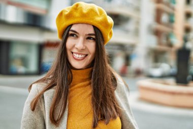 Genç İspanyol kız gülümseyerek şehirde mutlu mesut dikiliyor..