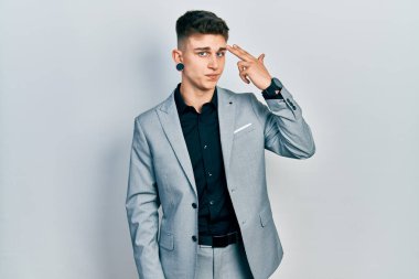 Kulakları genişlemiş, iş ceketi giymiş genç beyaz bir çocuk silah gibi elini ve parmaklarını havaya kaldırarak kendini vuruyor, intihar ediyor.. 