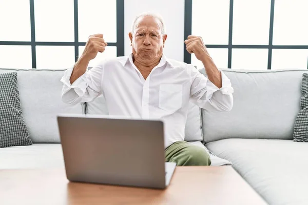 Hombre Mayor Usando Portátil Casa Sentado Sofá Mostrando Los Músculos — Foto de Stock