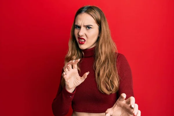 Young blonde woman wearing turtleneck sweater disgusted expression, displeased and fearful doing disgust face because aversion reaction. with hands raised